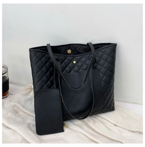 Macro detail of black quilted faux leather tote with metal magnetic closure and small pouch