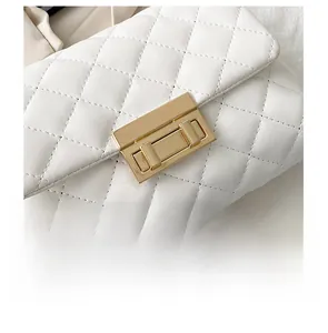 Detail view of the elegant golden texture lock on a white quilted leather shoulder bag