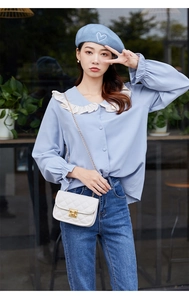 Détail d'un sac à bandoulière matelassé blanc avec chaîne dorée et fermoir métallique chic