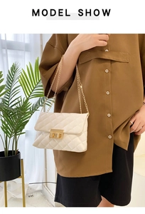 Detail of cream quilted shoulder bag with gold twist lock and chain strap on model
