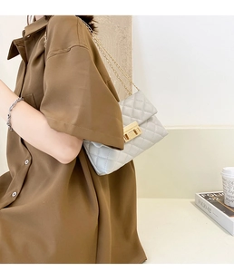 Detail shot of beige quilted shoulder bag with golden chain strap and twist lock
