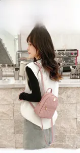 Side view of pink quilted mini backpack with gold logo plate worn by a model