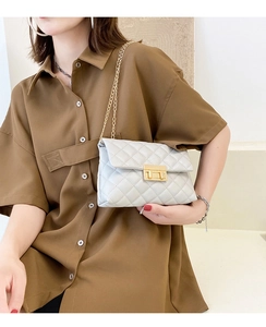 Close-up of quilted pattern and gold chain strap on the light grey crossbody bag