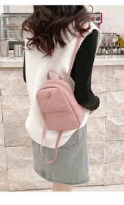 Pink quilted PU leather mini backpack with gold hardware shown on a model in a cafe