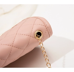 Gros plan du sac bandoulière matelassé rose montrant la texture et la chaîne dorée