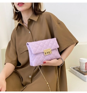 Close-up of lilac quilted crossbody bag with gold twist lock and chain strap on table