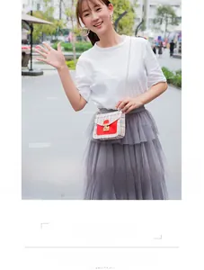 Detail of a plaid crossbody bag with a red flap and chain strap for summer outfits