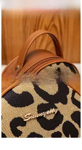 Dettaglio borsa leopardata in tela con logo dorato Sunnycity e manico in pelle marrone