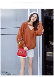 Detail of caramel knit sweater featuring V-neck cutout and floral embroidery on sleeves