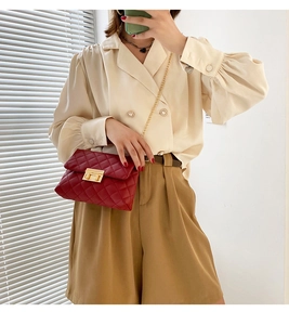 Quilted burgundy crossbody bag with gold chain strap shown on model in stylish outfit