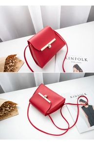 Detail view of red leather crossbody bag featuring a unique asymmetrical flap and gold clasp