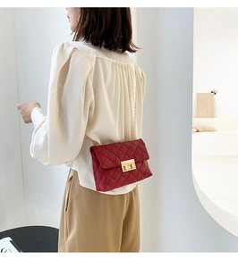 Detail of red quilted crossbody bag with gold chain strap and metallic twist lock