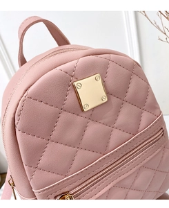 Detail of pink quilted mini backpack with a gold square metal plate and dual zippers