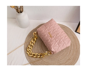 Detailed shot of pink quilted handbag with gold chain handle and metal brand logo
