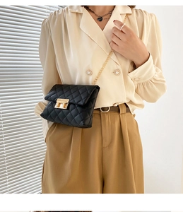 Close-up of black quilted shoulder bag with gold chain strap and metal turn-lock