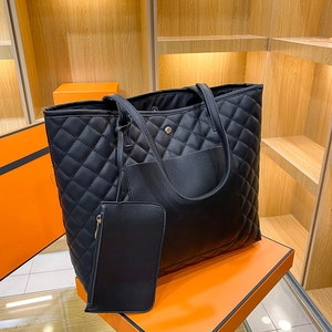 Quilted black leather tote bag set with matching small pouch and orange gift box background