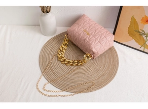 Detailed view of pink quilted handbag with chunky gold chain handle and metal strap