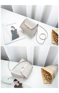 Detail view of a light gray PU leather crossbody bag with a golden turn-lock closure