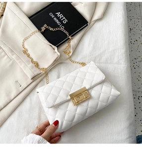 Close-up of white quilted crossbody bag with gold chain strap and rectangular metal lock