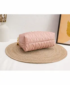Detail of pink quilted texture and gold chain on the crossbody bag with neat stitching