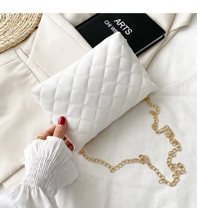 Close-up of quilted white leather shoulder bag with golden chain and diamond stitching