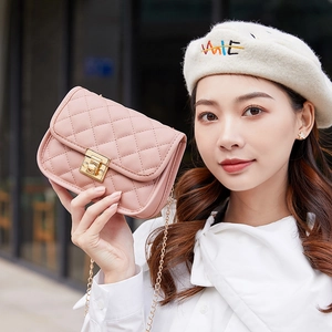 Petit sac carré rose matelassé avec chaîne dorée porté par un mannequin en ville