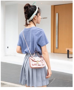 Lifestyle view of a pink PVC crossbody bag with daisy prints and a gold lock