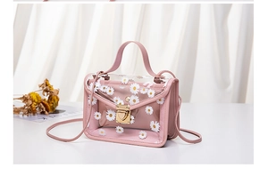 Detailed shot of pink transparent crossbody bag with white daisy prints and metal clasp