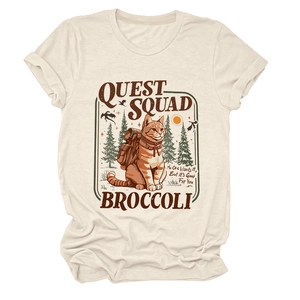 Dettaglio della stampa gatto Quest Squad su t-shirt crema con motivo di boschi e monti
