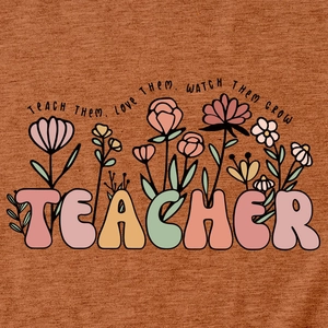 Détail macro du t-shirt enseignant terracotta avec motif floral et citation inspirante