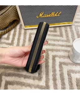 Détail de la fermeture éclair dorée sur cette pochette rectangulaire en similicuir noir