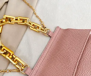 Detail einer rosa Handtasche aus genarbtem Leder mit grober goldener Kette und Riemen
