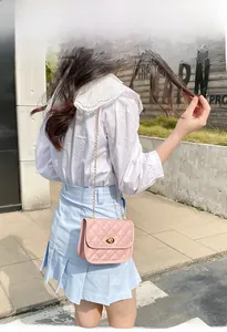 Pink quilted square crossbody bag with gold chain strap shown on model outdoors