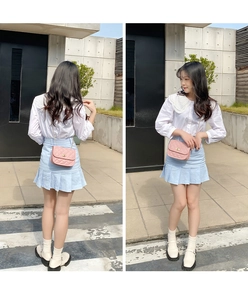 Pink quilted chain crossbody bag styled with a white lace shirt and blue pleated skirt