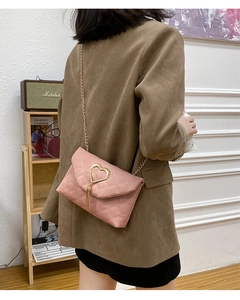 Pink quilted shoulder bag with gold heart clasp and tassel shown in a lifestyle interior