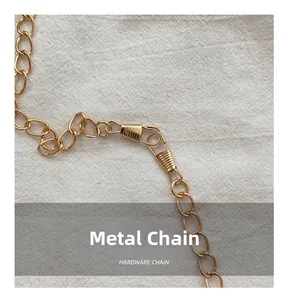 Close-up of golden hardware chain with spring hooks on textured linen background