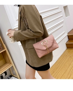 Detailed view of pink quilted chain bag with large golden heart-shaped clasp on a model