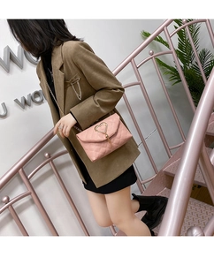 Detailed view of pink quilted crossbody bag with golden heart-shaped buckle and chain strap