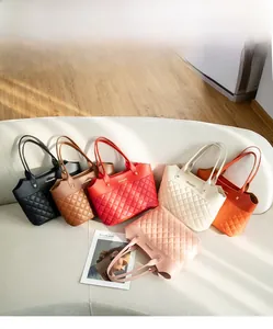 Détail de cabas matelassés en six couleurs présentés sur un canapé blanc crème