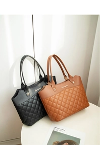 Détail du motif matelassé et du logo doré sur les sacs cabas en cuir noir et marron