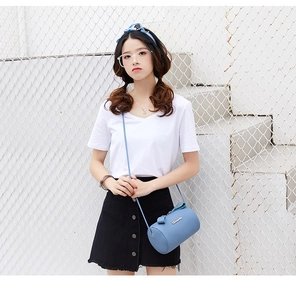 Close-up of sky blue lychee pattern cylindrical crossbody bag with gold logo and strap
