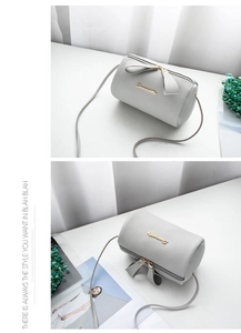Macro detail of grey lychee textured barrel bag featuring gold logo and dual zippers