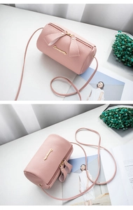 Detail view of pink lychee pattern barrel crossbody bag with golden metal logo and zipper