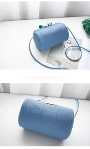 Close-up of blue litchi pattern cylinder bag with gold metal logo and zipper detail