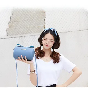 Sky blue cylindrical crossbody bag with lychee texture and gold logo shown on model