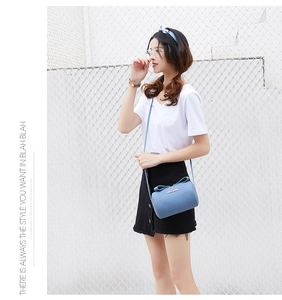 Close-up of light blue cylinder bag featuring leather bow and metallic logo detail