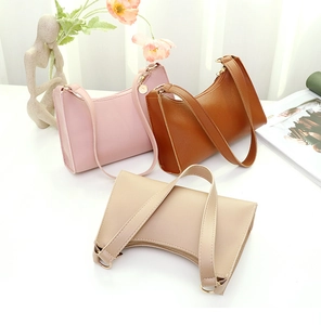 Schicke Halbmond-Schultertaschen in Pastellrosa, Karamellbraun und Beige auf dem Tisch