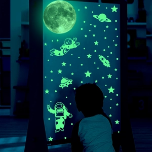 Luminous wall stickers set featuring glowing astronauts and planets in a dark bedroom