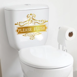 Detail eines goldenen Please Flush Aufklebers mit Vintage-Muster auf weißem Spülkasten