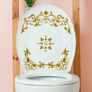Nahaufnahme der goldenen Barock-Aufkleber auf einem weißen WC-Deckel im Badezimmer